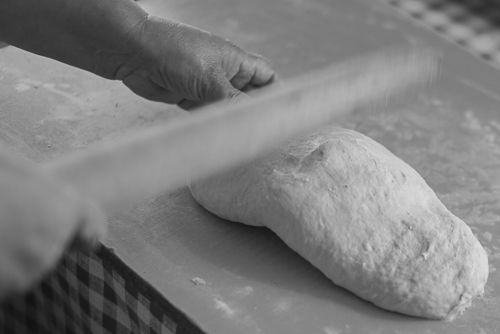 Picture showing the owner hitting the dough with a rolling pin