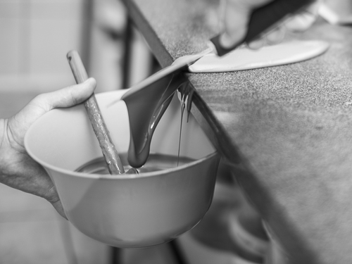 Forcing molten chocolate enter a bowl by means of a spatula